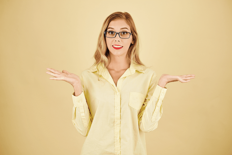 Woman in glasses holding out both hands against a yellow background