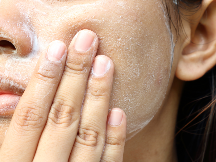 Person applying exfoliating cream to their cheek