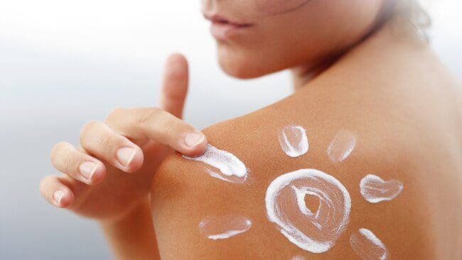 Person applying sunscreen to their shoulder