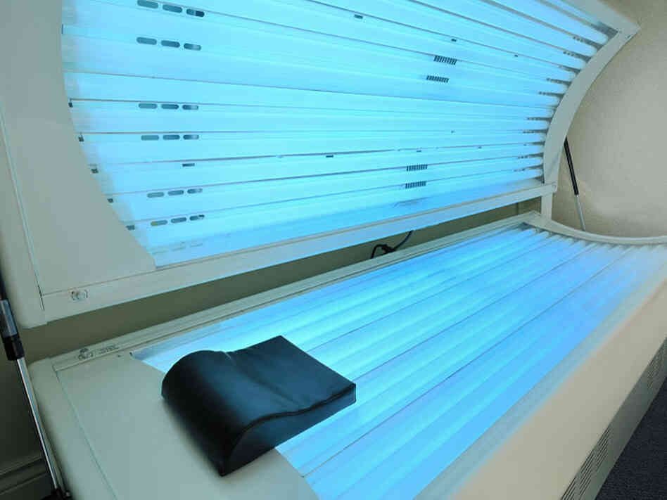 Open UV tanning bed with illuminated tubes